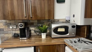 Eine Küche mit Holzschränken, einer Kaffeemaschine, einer Mikrowelle und einem Kühlschrank.