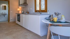 A modern kitchen with a central island, a built-in oven, a sink, and a window with wooden frames. - Lavanda by Interhome (Fucecchio)