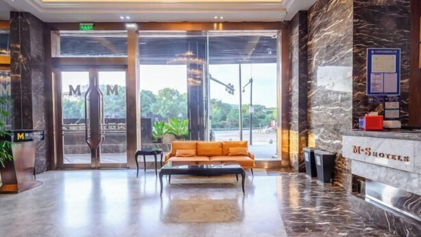 A hotel lobby with a reception desk, a sofa, and a marble floor. - MEISU Meisu Art Hotel (Ninghai Xizi International Branch) (Ninghai)