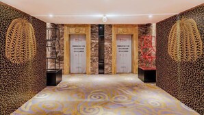 A hotel lobby with a patterned carpet, two doors with signage, and decorative wall panels. - MEISU Meisu Art Hotel (Ninghai Xizi International Branch) (Ninghai)