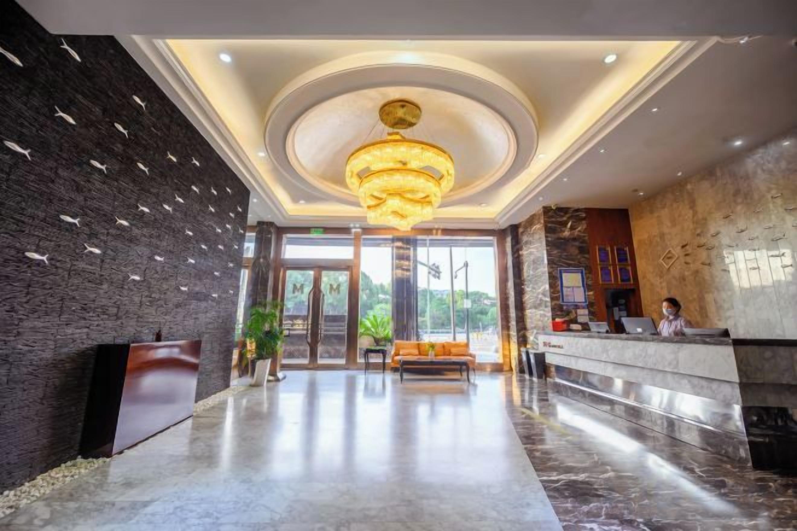 Eine Hotelhalle mit einer Rezeption, einer Sitzecke und einer Chandelüster.