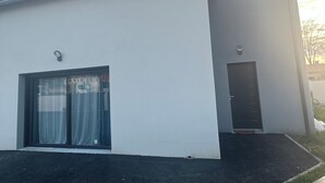 Un edificio moderno con tetto piatto, un'ampia porta scorrevole in vetro e una piccola porta.
