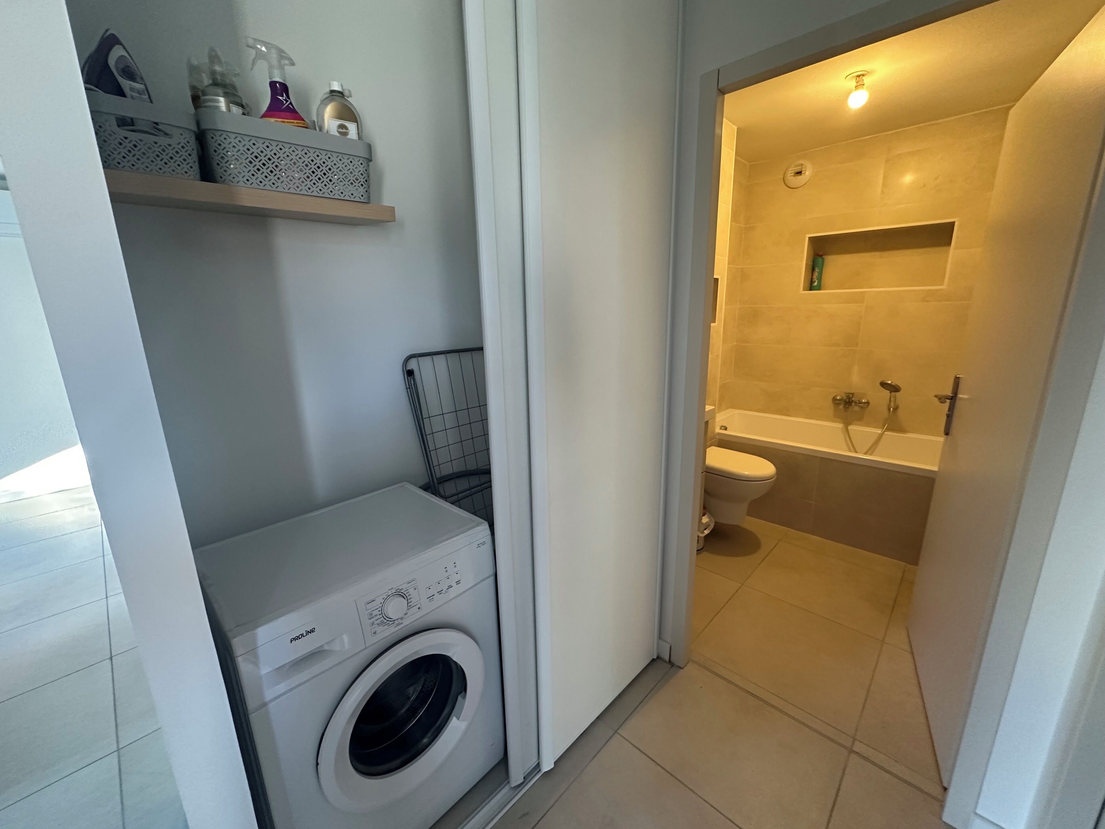 A compact bathroom with a washing machine, a toilet, and a bathtub.