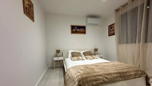 Una camera da letto con un letto, comodini, un climatizzatore e tende.