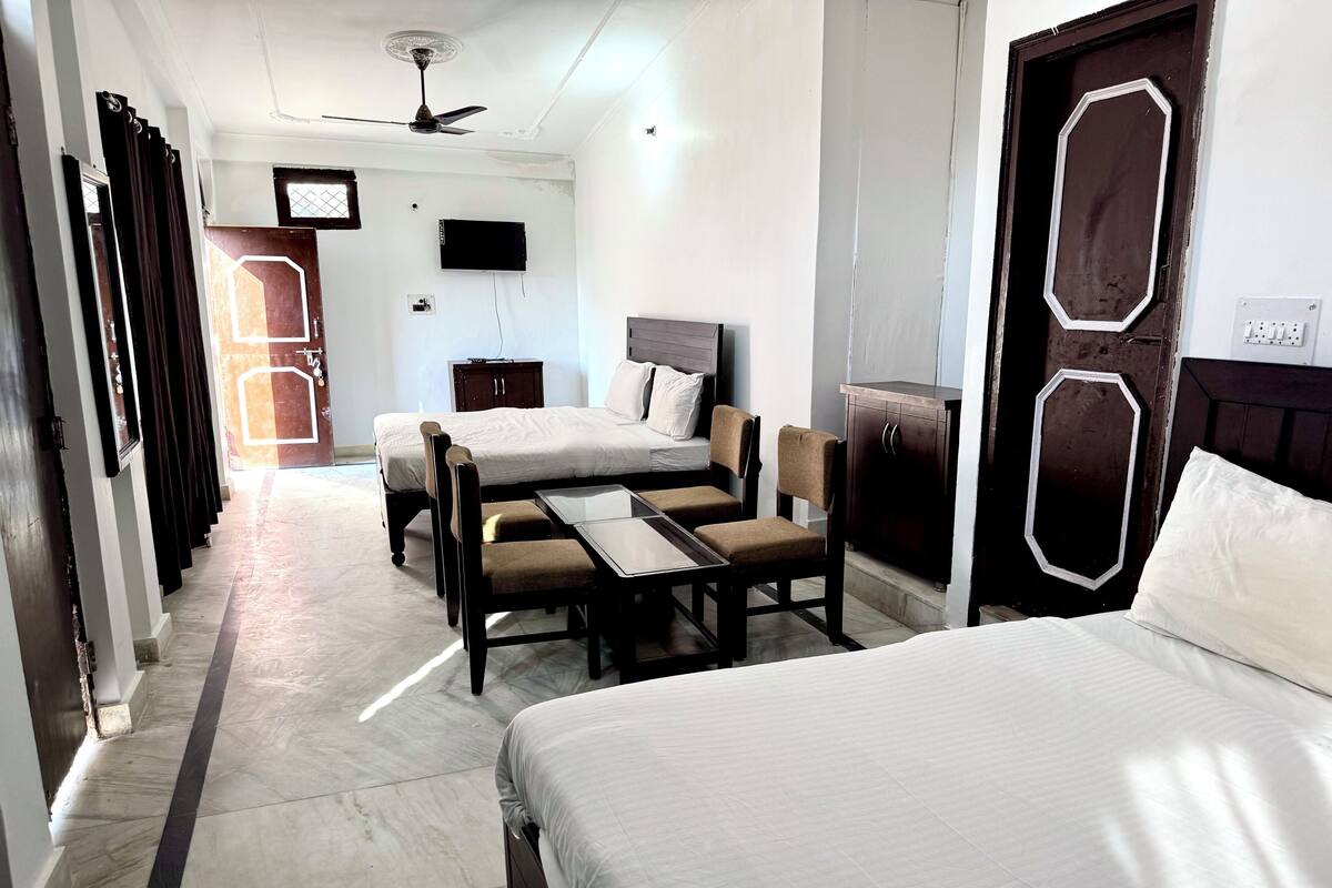 A hotel room with a bed, a desk, two chairs, a television, and a wardrobe.