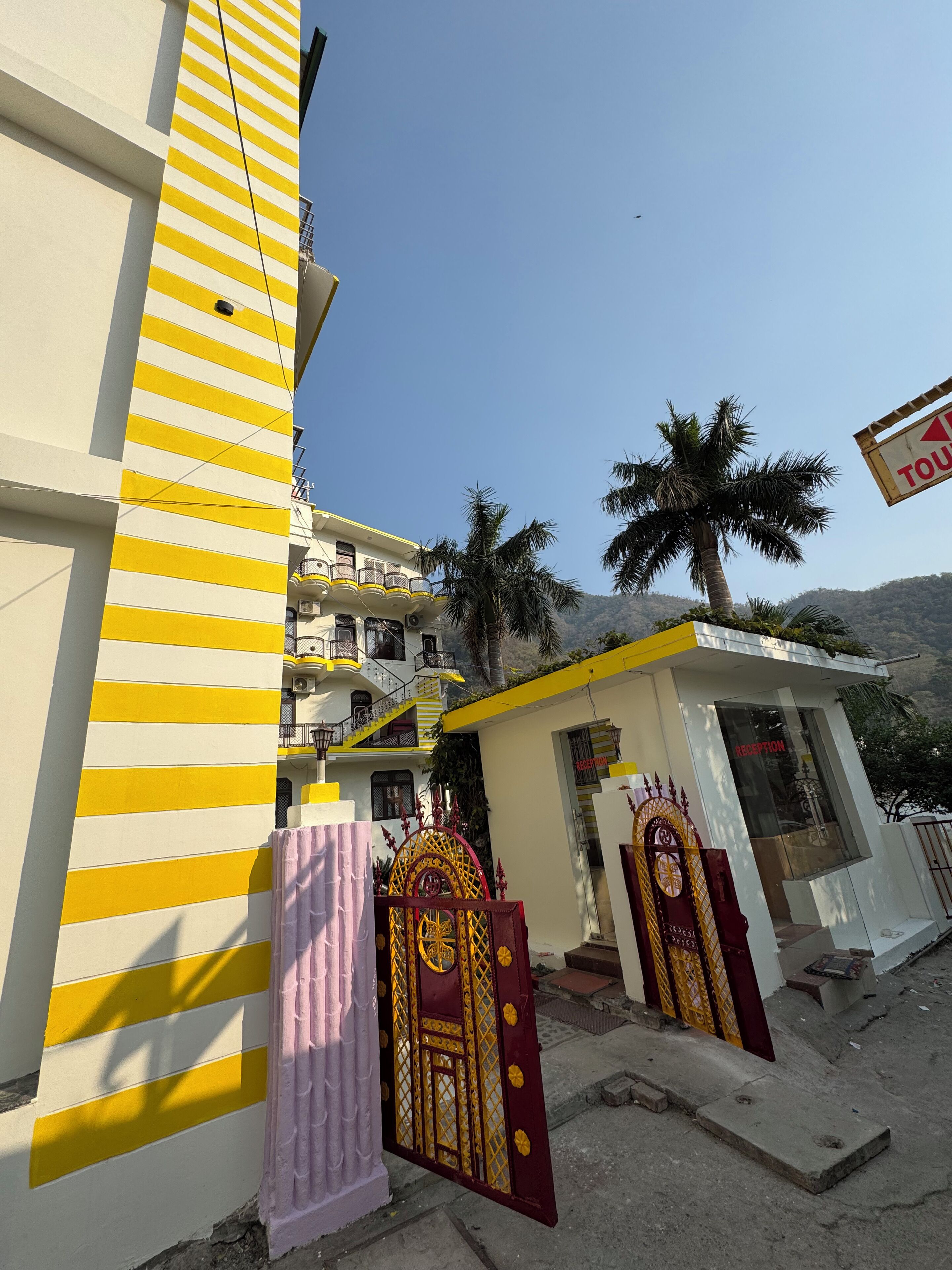 A building with yellow and white stripes, a reception area, and a palm tree.