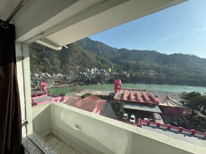 A balcony with a view of a town and a river. - Nirvana Riverside Resort (Rishikesh)