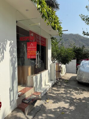 A reception area with a sign for Nirvana Riverside Resort, including contact information and room types. - Nirvana Riverside Resort (Rishikesh)