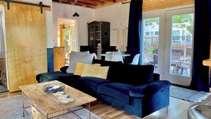 A cozy living room with a dark blue sofa, a wooden coffee table, and a black cabinet. - Urban Cottage. Walkable. Sweet Spring Stay (Austin)
