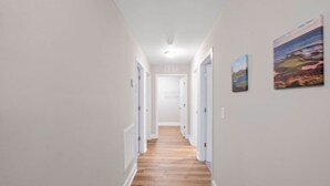 A narrow hallway with wooden flooring and white walls. - The Cedar at Ducks Landing (Aberdeen)