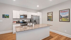 A modern kitchen with white cabinets, stainless steel appliances, and a granite countertop. - The Cedar at Ducks Landing (Aberdeen)