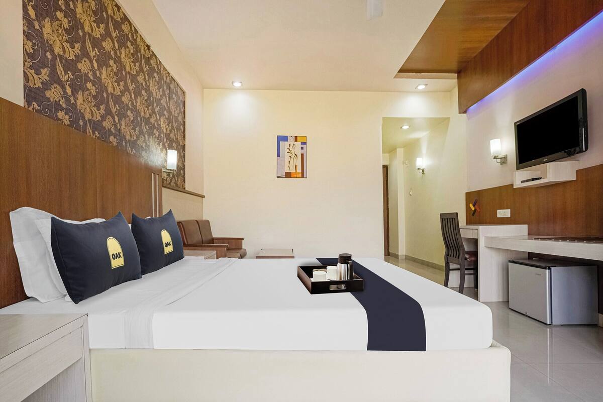 Ein modernes Hotelzimmer mit einem großen Bett, einem Schreibtisch, einem Flachbildfernseher und einer kleinen Kühlbox.
