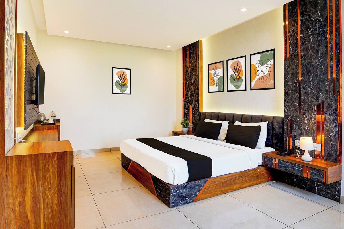 Ein modernes Hotelzimmer mit einem großen Bett, einem Holztisch und einer Wand mit Marmorverkleidung.