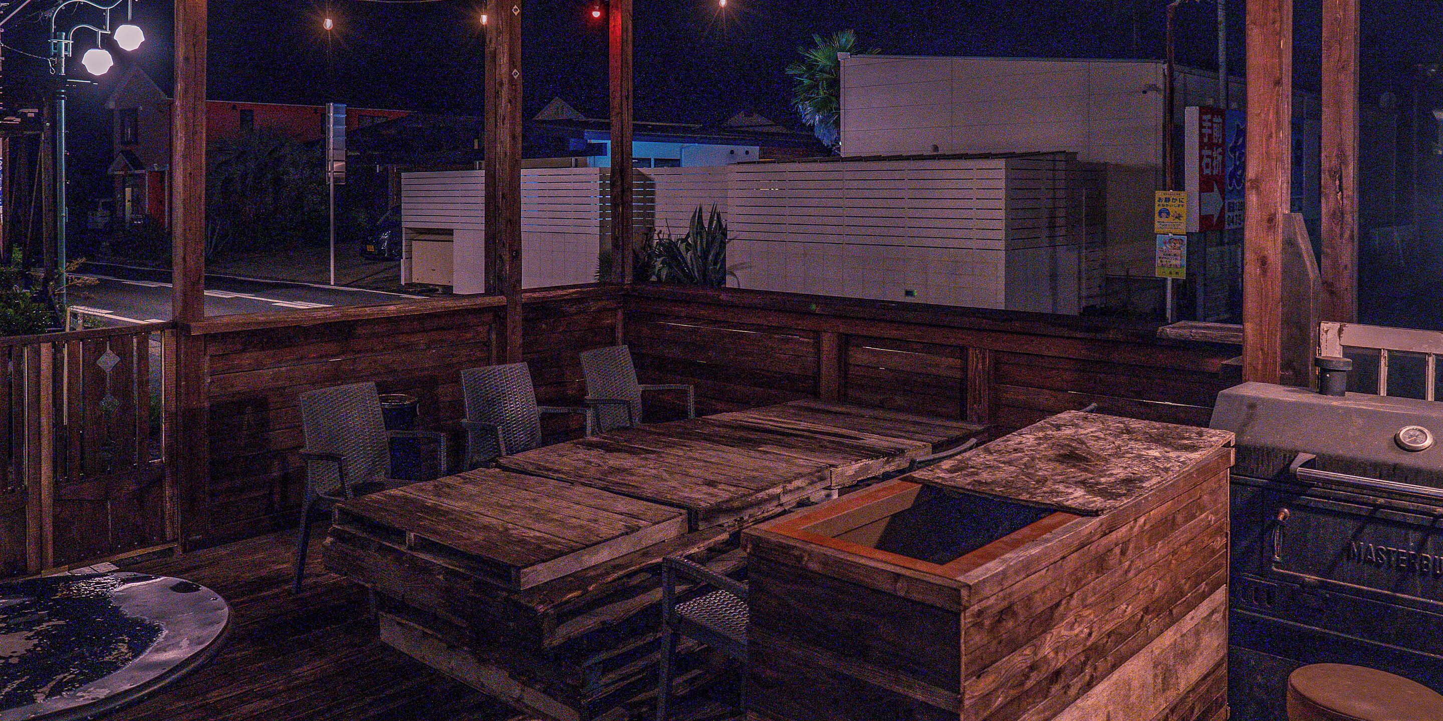 A wooden deck with outdoor seating, a hot tub, and a barbecue grill.