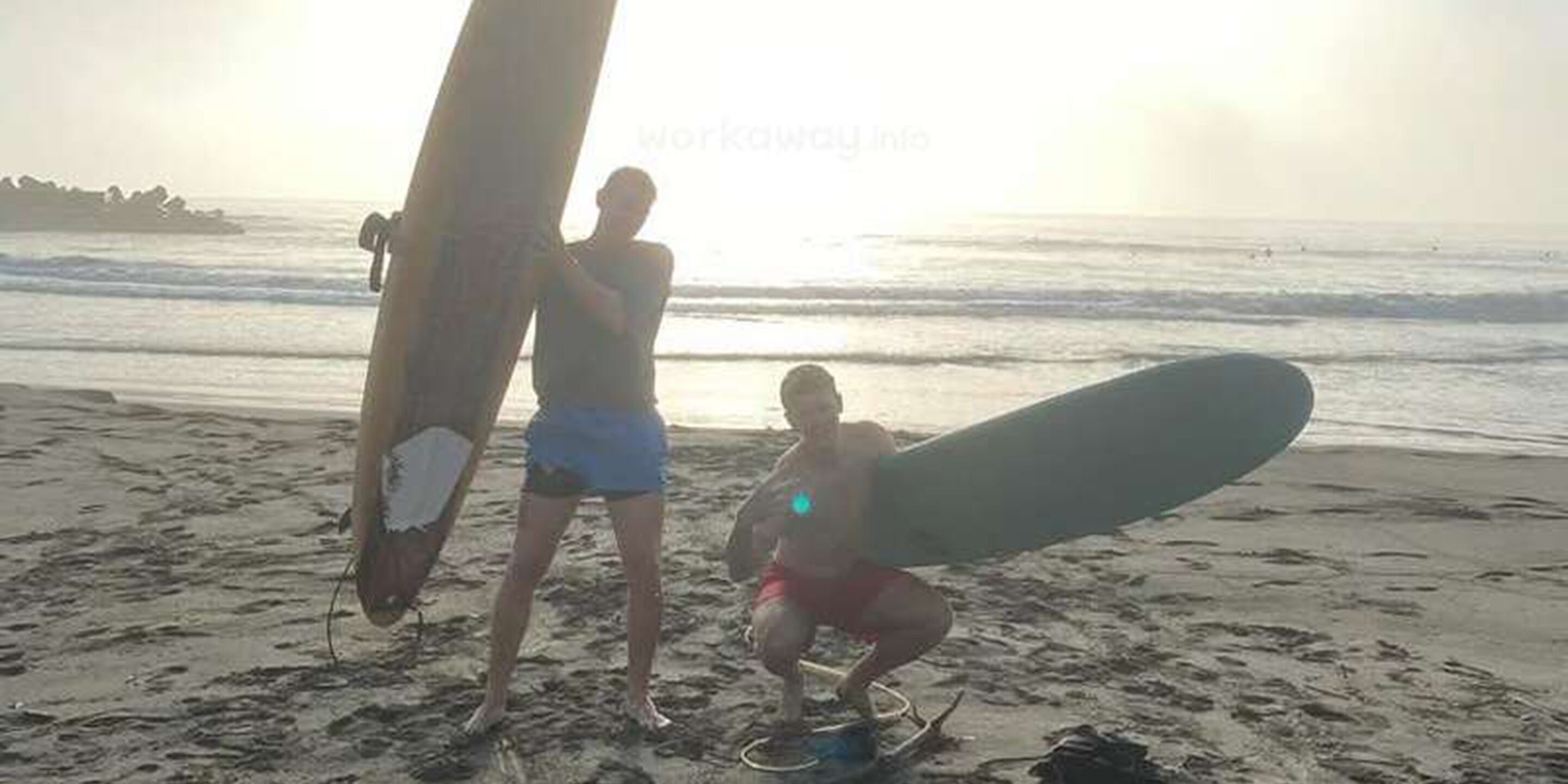 A beach scene with a surfboard and a person holding it.