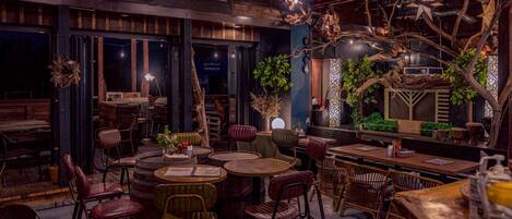 A restaurant interior with round tables and chairs, wooden decor, and hanging star decorations.