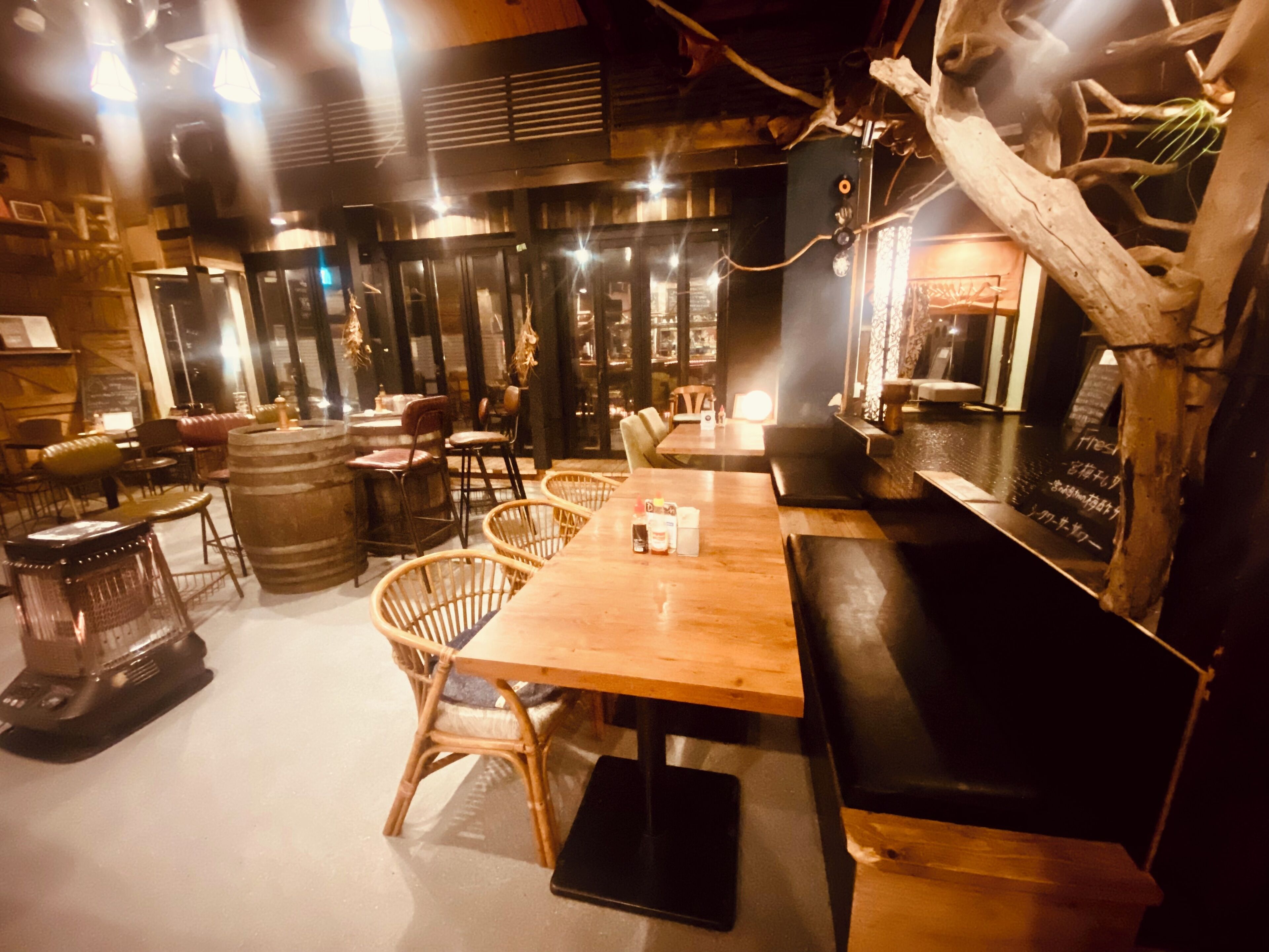 Un restaurant chaleureux avec des tables et des chaises en bois, un coin bar et un tableau affichant le menu.