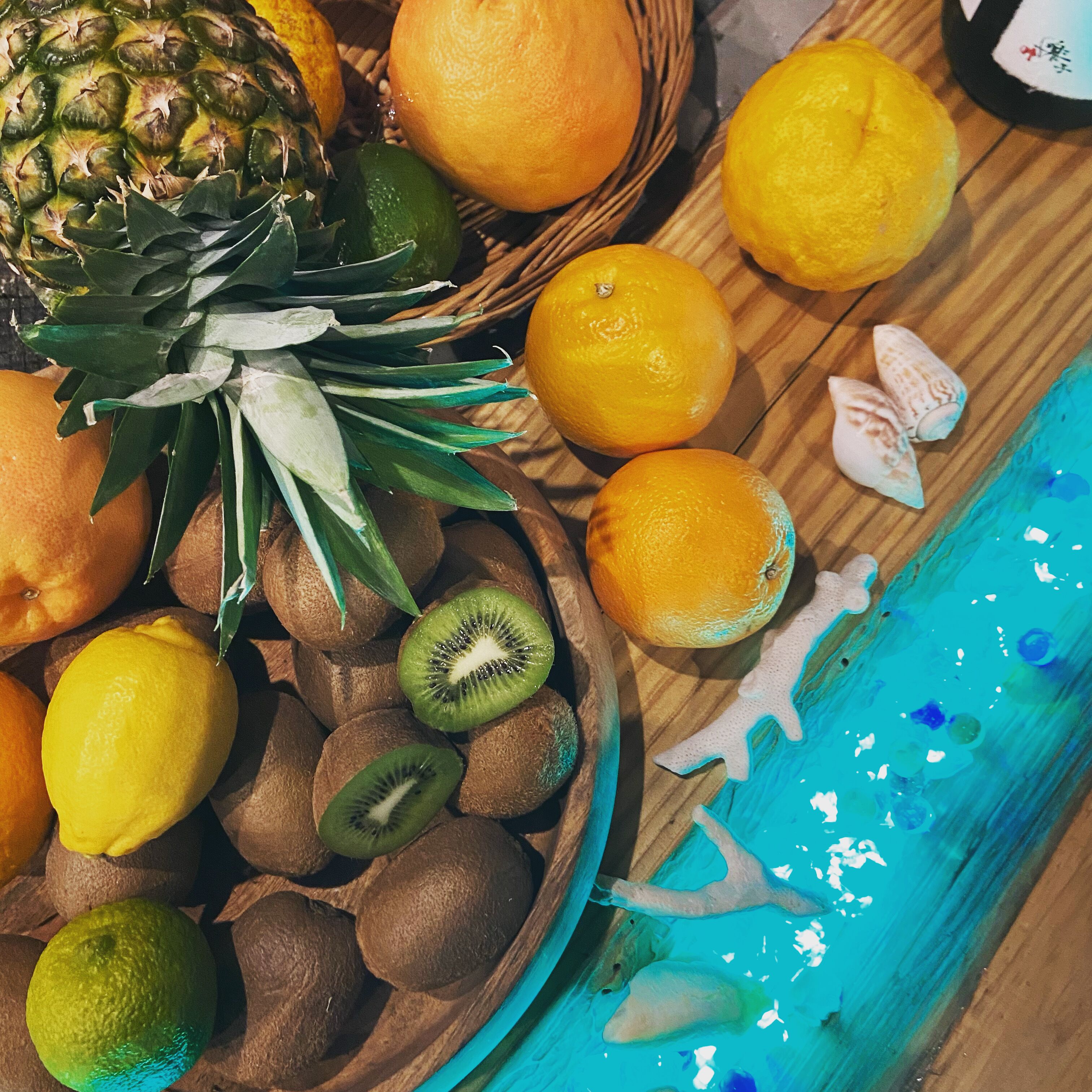 Una mesa de madera con un bol lleno de frutas variadas y un pez decorativo.