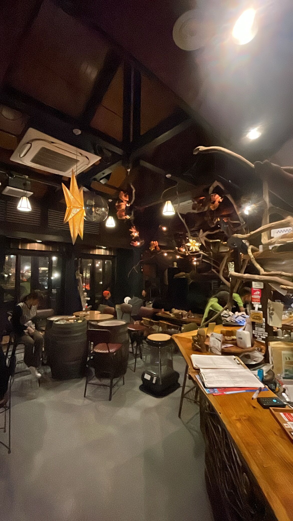 Un accogliente ristorante con tavoli e sedie in legno, decorazioni appese e un'area bar.