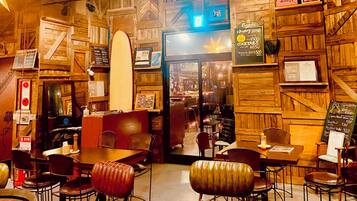 Un restaurante acogedor con paredes de madera y una decoración con tabla de surf. Mesas y sillas dispuestas para comer.
