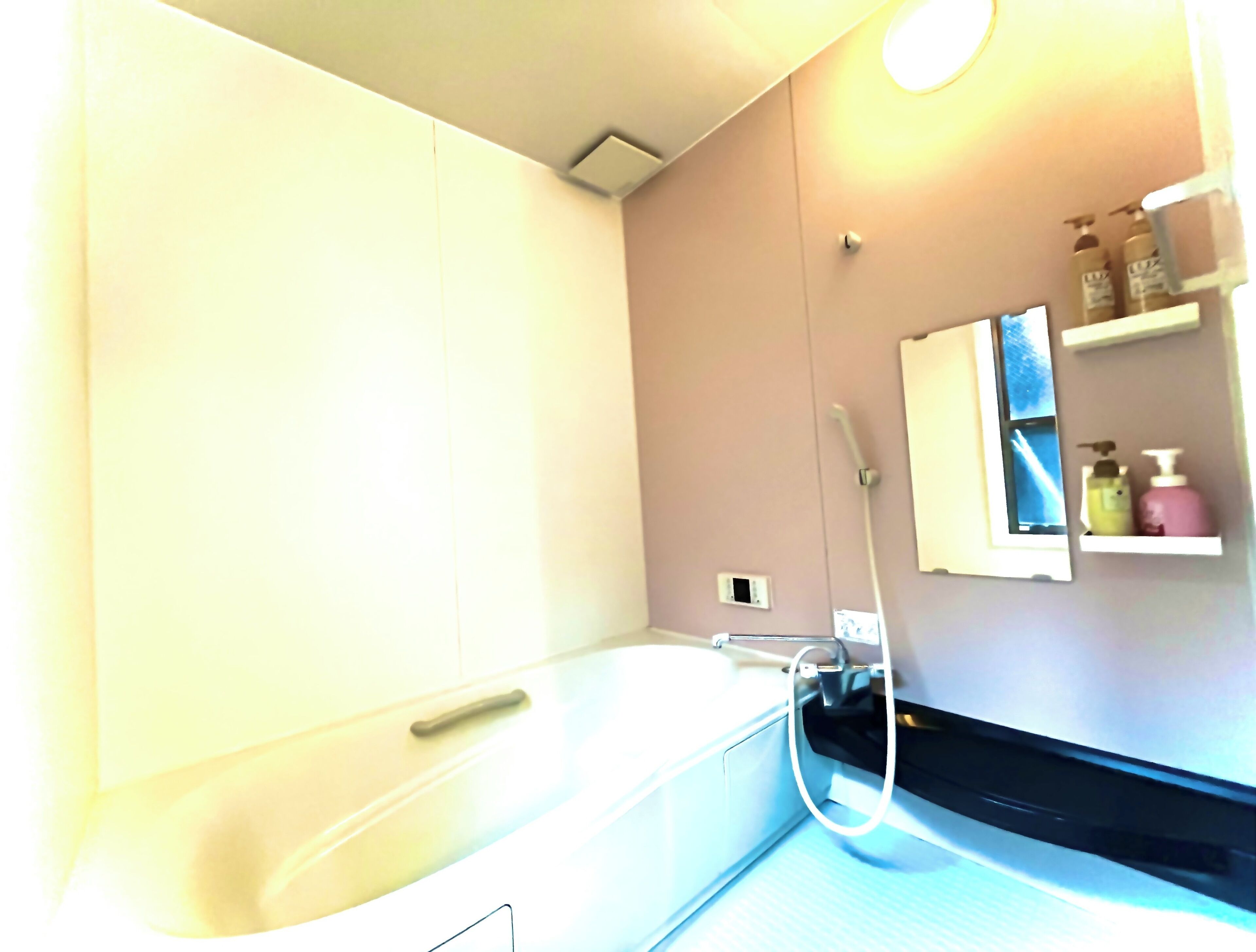 Un baño con bañera, ducha y espejo con un estante arriba.