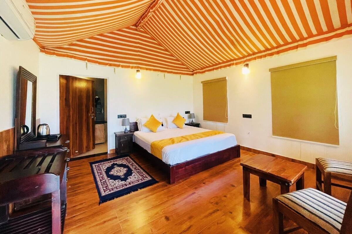 A bedroom with a striped canopy bed, wooden furniture, and a large window.