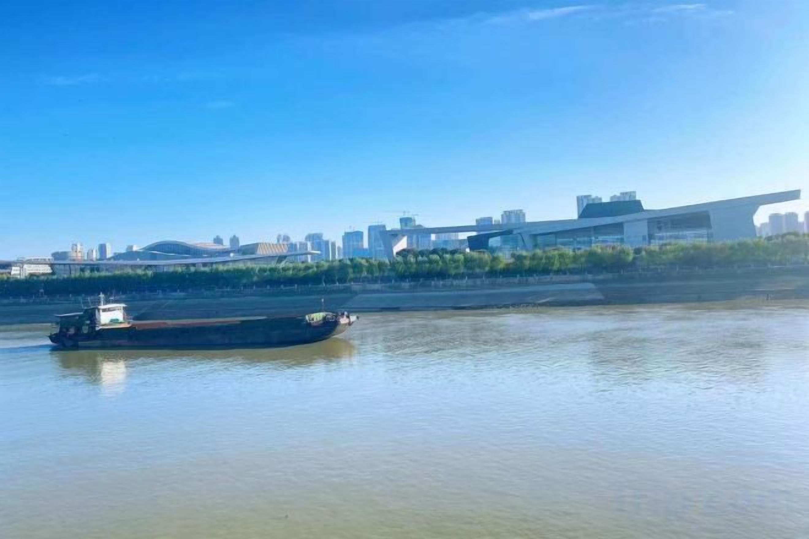 A river with a boat and a city skyline in the background.