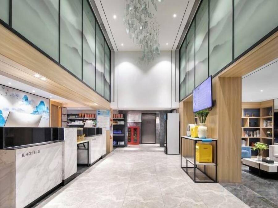 Un hall d’hôtel comprenant un comptoir d’accueil, un écran de télévision et un espace salon avec une table basse.
