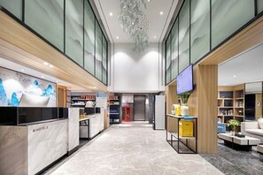 Et hotel lobby med en receptionsdisk, et tv-skærm og et siddeområde med et sofabord.