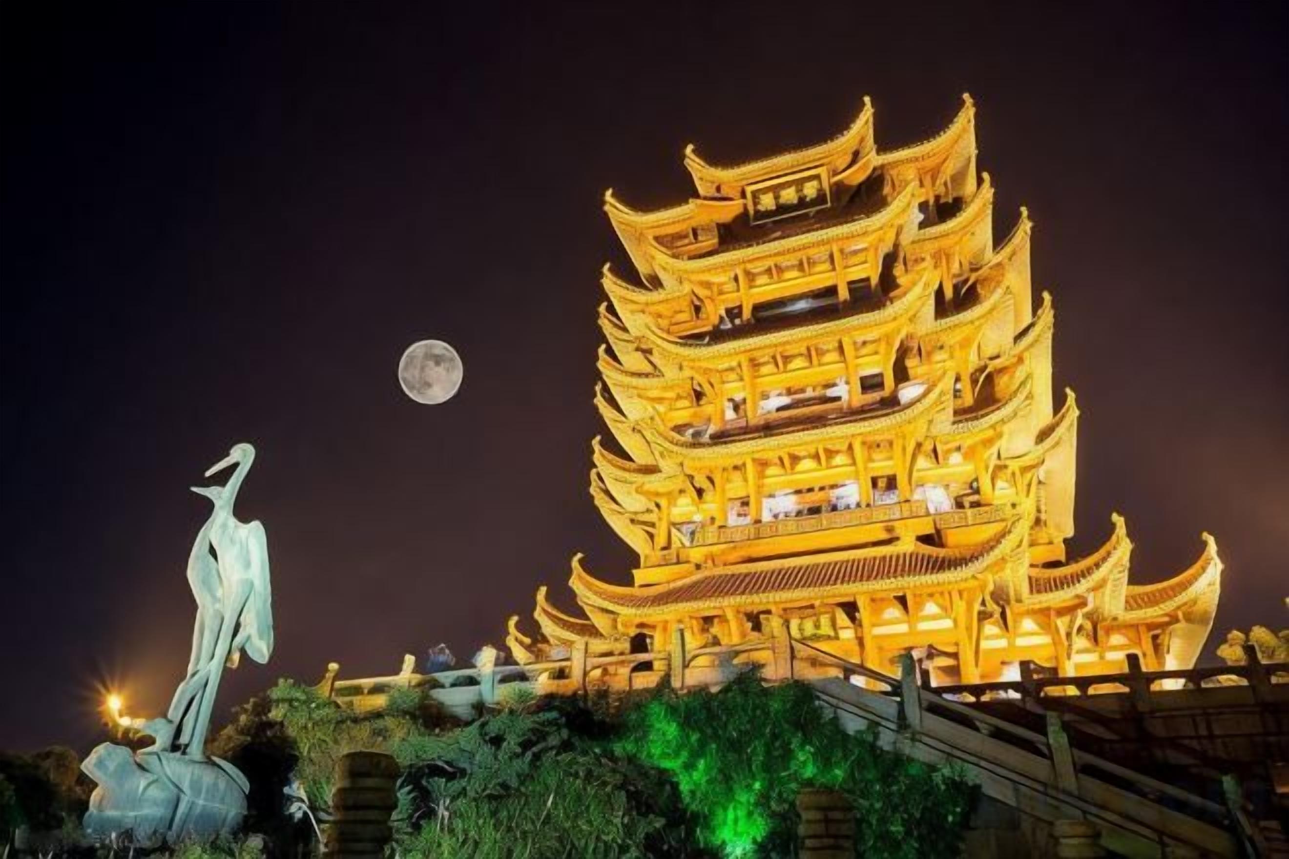 A multi-tiered building with a statue in front.