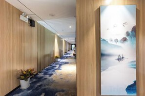 A hallway with wooden paneling, a large painting of a landscape, and potted plants. - H Hotel (Wuhan Hanzheng Street Chongren Road Metro Station Jiangtan Branch) (Wuhan)