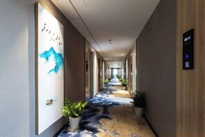 A hotel hallway with a carpeted floor, a wall with a blue abstract painting, and a sign indicating room number 8511. - H Hotel (Wuhan Hanzheng Street Chongren Road Metro Station Jiangtan Branch) (Wuhan)
