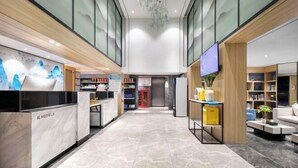 Un vestíbulo de hotel con mostrador de recepción, zona de estar y una escalera que conduce a los pisos superiores.