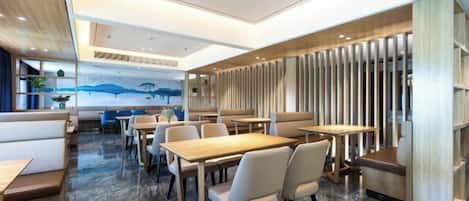 Un restaurante moderno con suelo de mármol, mesas de madera y asientos acolchados.