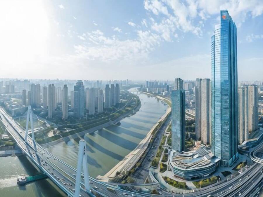 A high-rise building with a modern glass facade, surrounded by a dense urban environment with multiple high-rise buildings and a river.