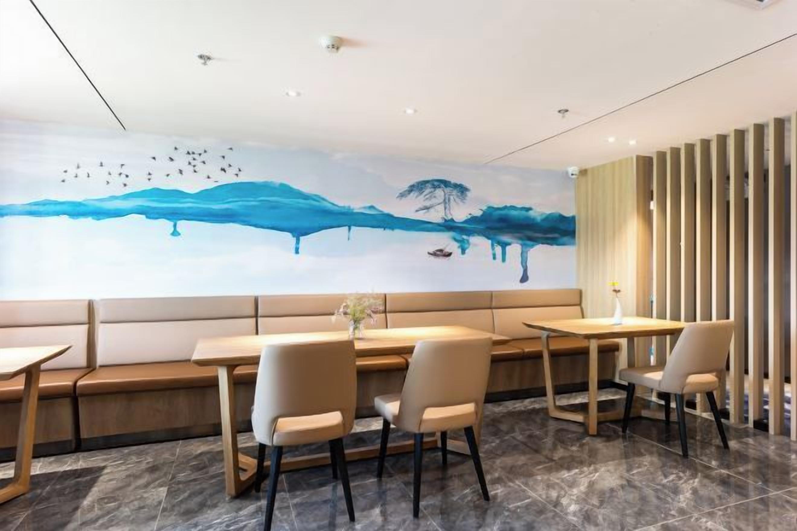 Un espace repas moderne agrémenté d’une fresque murale, de sièges et offrant une vue sur l’extérieur.