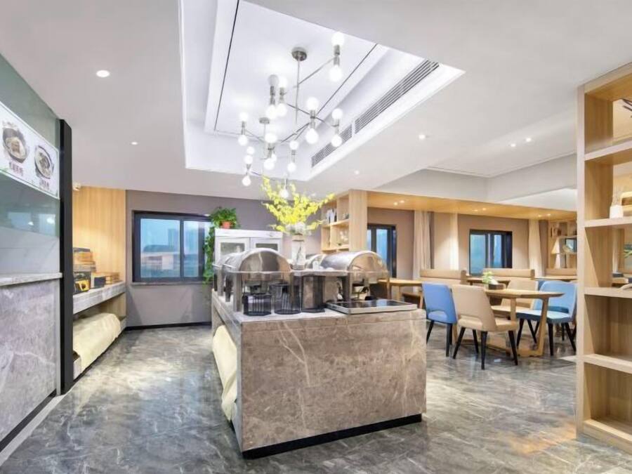 Rebedor modern d'hotel amb taulell de recepció de marbre, una illa central amb seients i una zona de dinar amb cadires blaves.