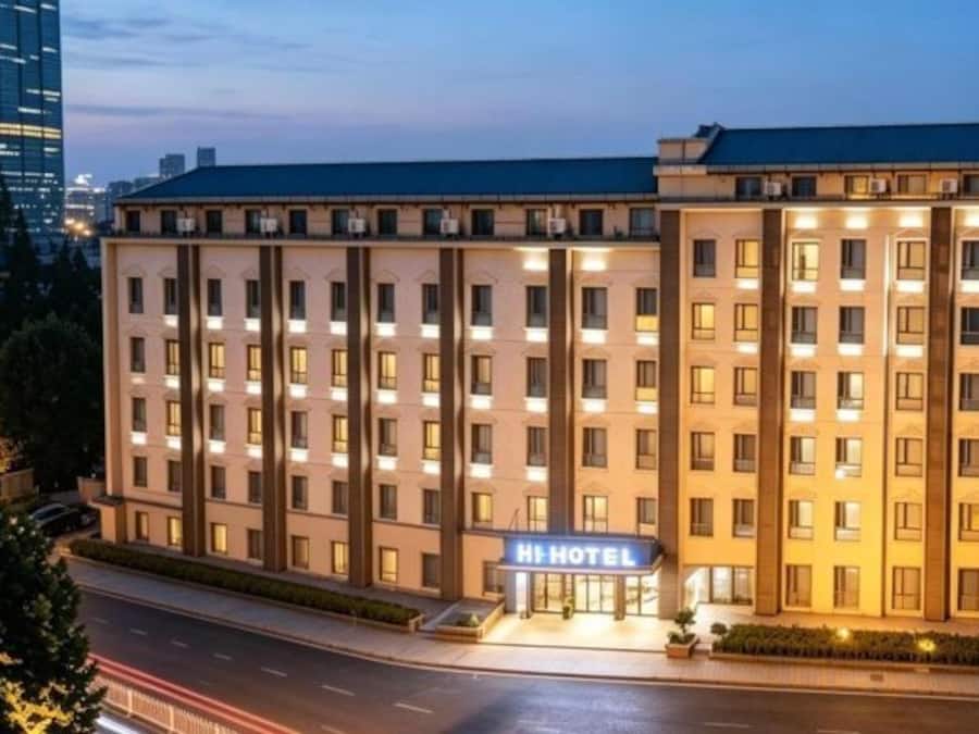 A multi-story hotel with a prominent 'Hi Hotel' sign, a well-lit facade, and a modern architectural design.