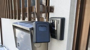 A security box and a doorbell on a building's exterior wall. - KARAHORI NODOKA (Osaka)