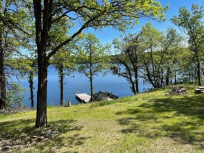 A lakeside cabin with a dock and a grassy area.