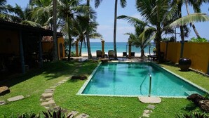 Una piscina rectangular con agua azul cristalina, rodeada por un césped cuidado y palmeras.