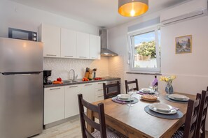 Eine moderne Küche mit weißen Schränken, einem eingebauten Backofen und einem Essbereich mit einem Holztisch, gedeckt für zwei Personen.