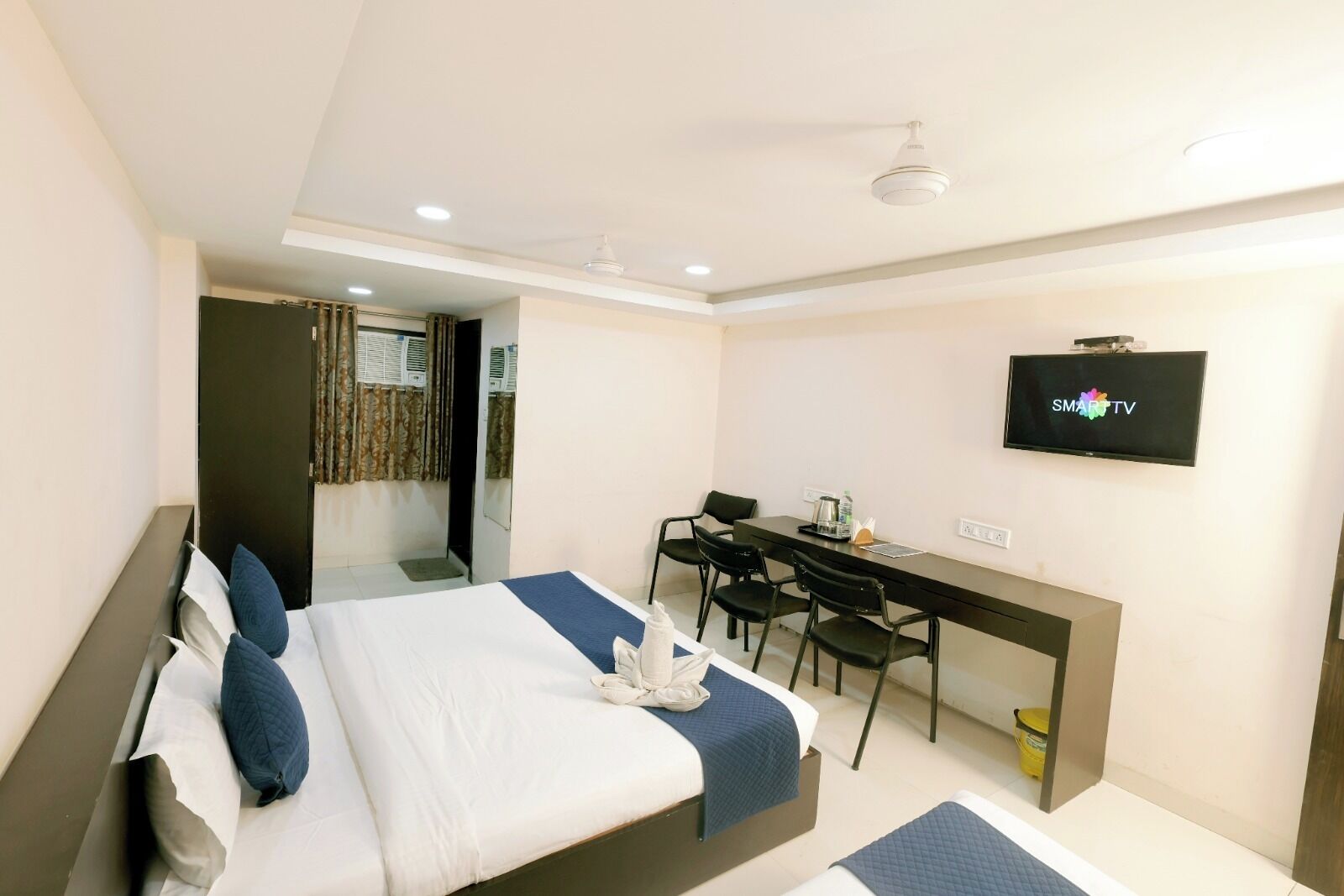 A hotel room with a bed, a desk, a chair, a television, and a bathroom door.