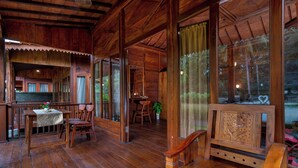 A wooden interior with a dining area, a bench, and a table with a flower arrangement.