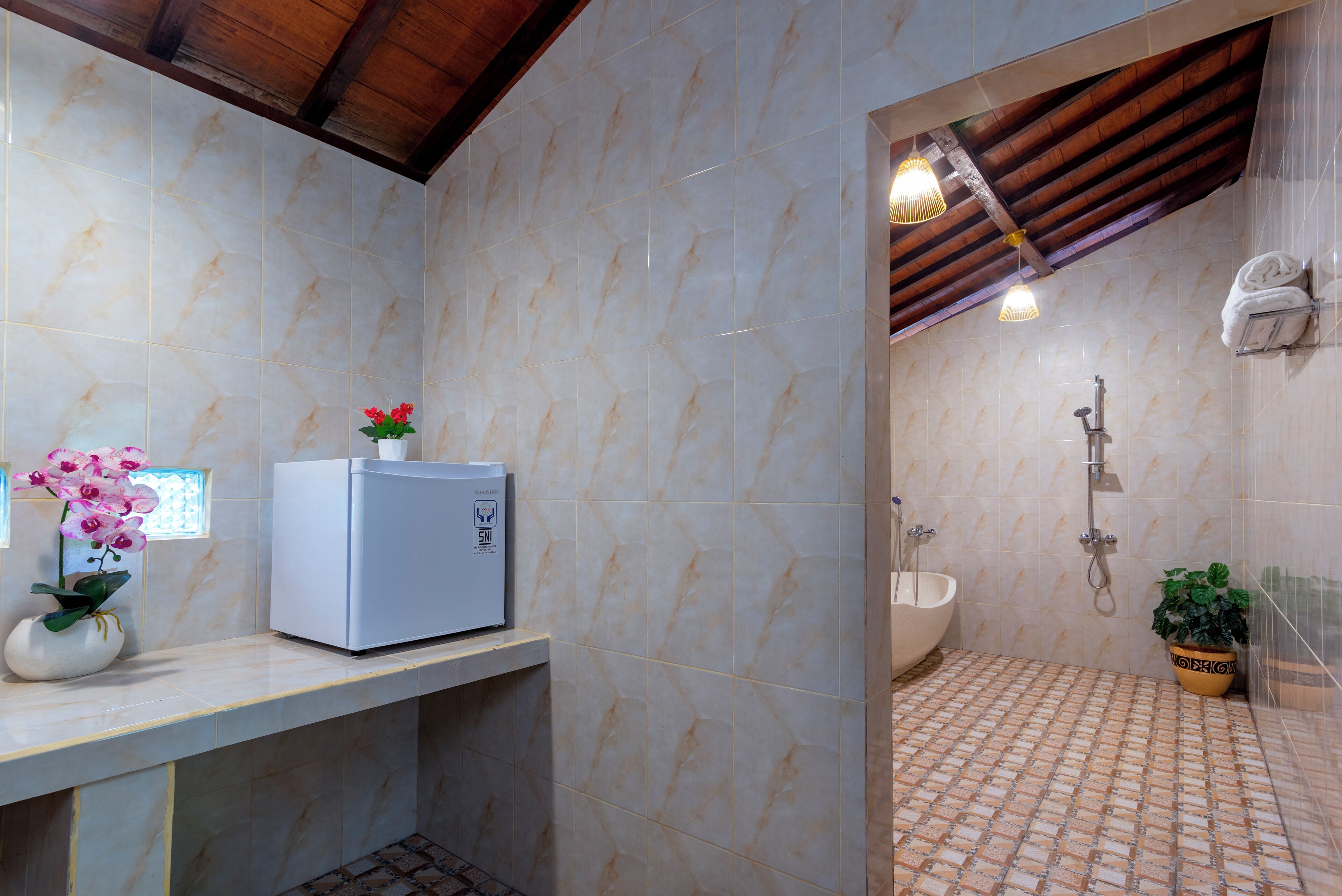 Een badkamer met een marmeren vloer, een wastafel, een douche en een kleine koelkast op een aanrecht.
