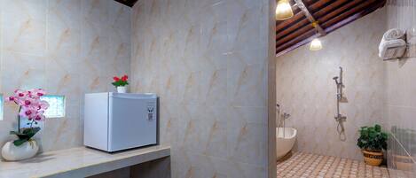 Un baño con piso de mármol, lavamanos, ducha y un refrigerador pequeño sobre una encimera.