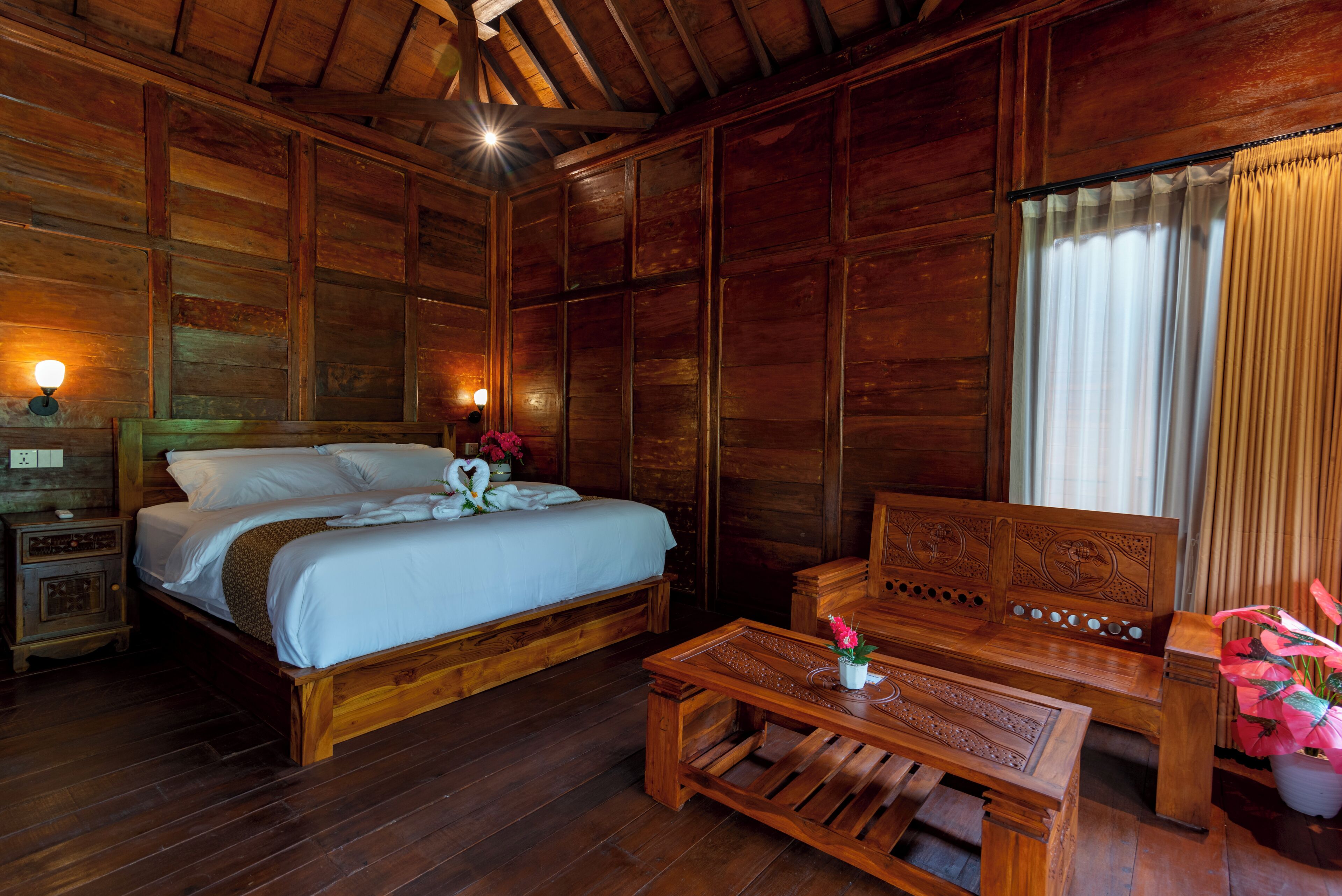 A wooden room with a bed, a wooden bench, and a nightstand.