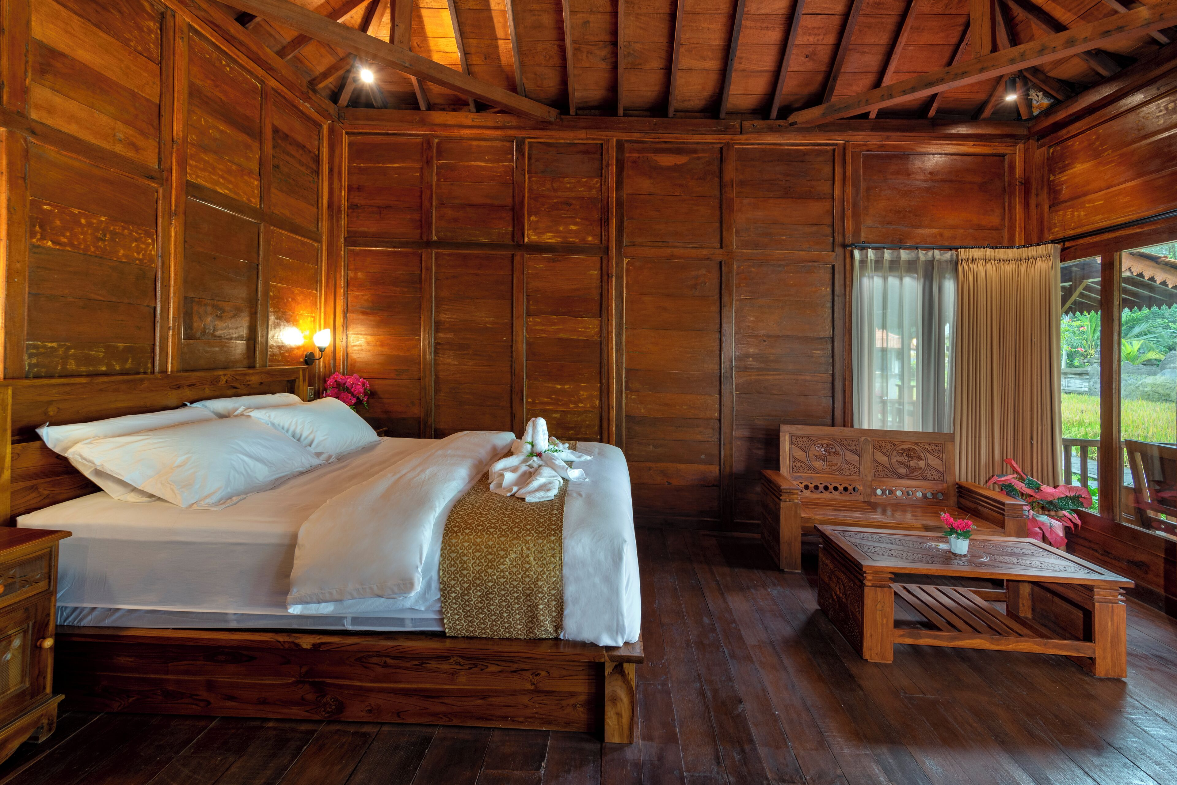 A wooden room with a bed, a table, and a bench.