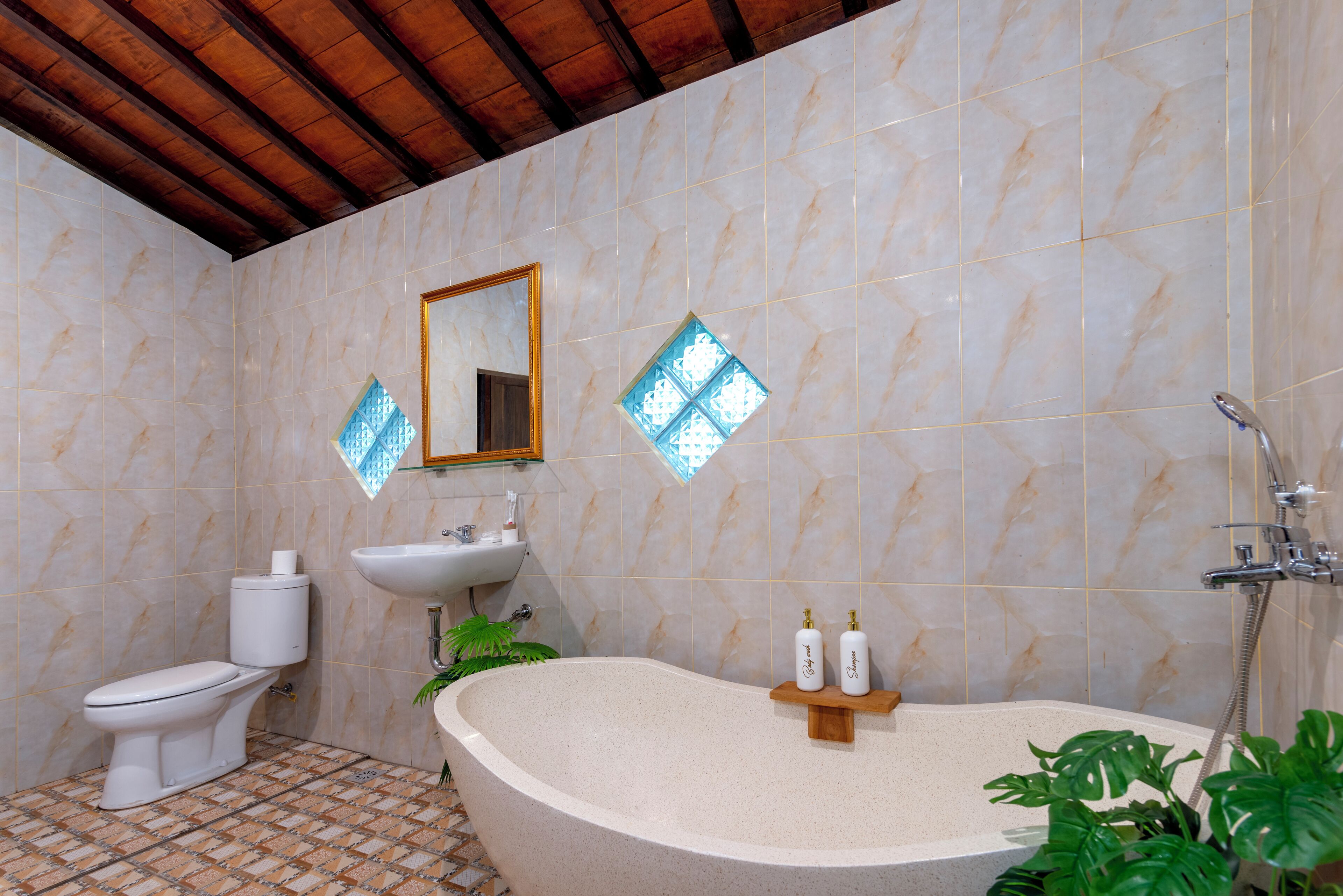 Un baño con una bañera independiente, un inodoro, un lavamanos y un espejo en la pared.