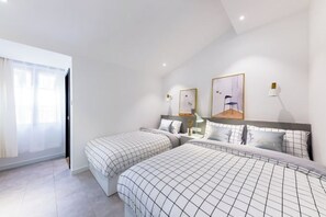 Una habitación de hotel moderna con dos camas, un ventanal grande y obras de arte en las paredes.